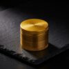 Fine Grinder 2.0 in Gold auf Schiefer Fine Grinder 2.0 aus Aluminium in Royal Gold auf dunklem Schiefer - hochwertiger Grinder von URBAN LEAF